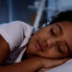 An adorable African-American girl sleeping in bed at home.