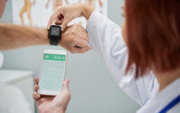 A doctor helping a patient sync their smart watch to a mobile application.