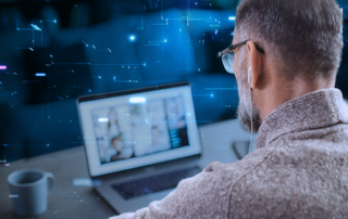 A man sitting at his computer with technological visual effects surrounding him.